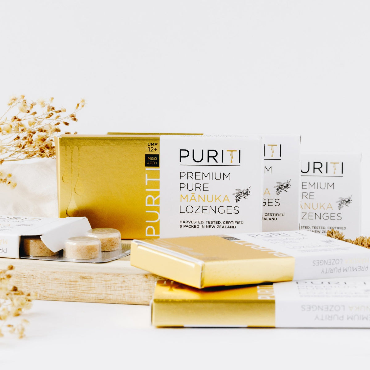 Puriti Genuine Manuka Honey Lozenges UMF 12+ box of 8, 3 boxes arranged on a board, displaying the lozenge sleeve